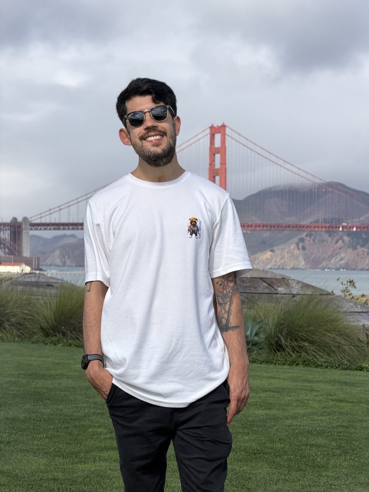 João Gabriel sorrindo, de camiseta branca, com a ponte Golden Gate ao fundo